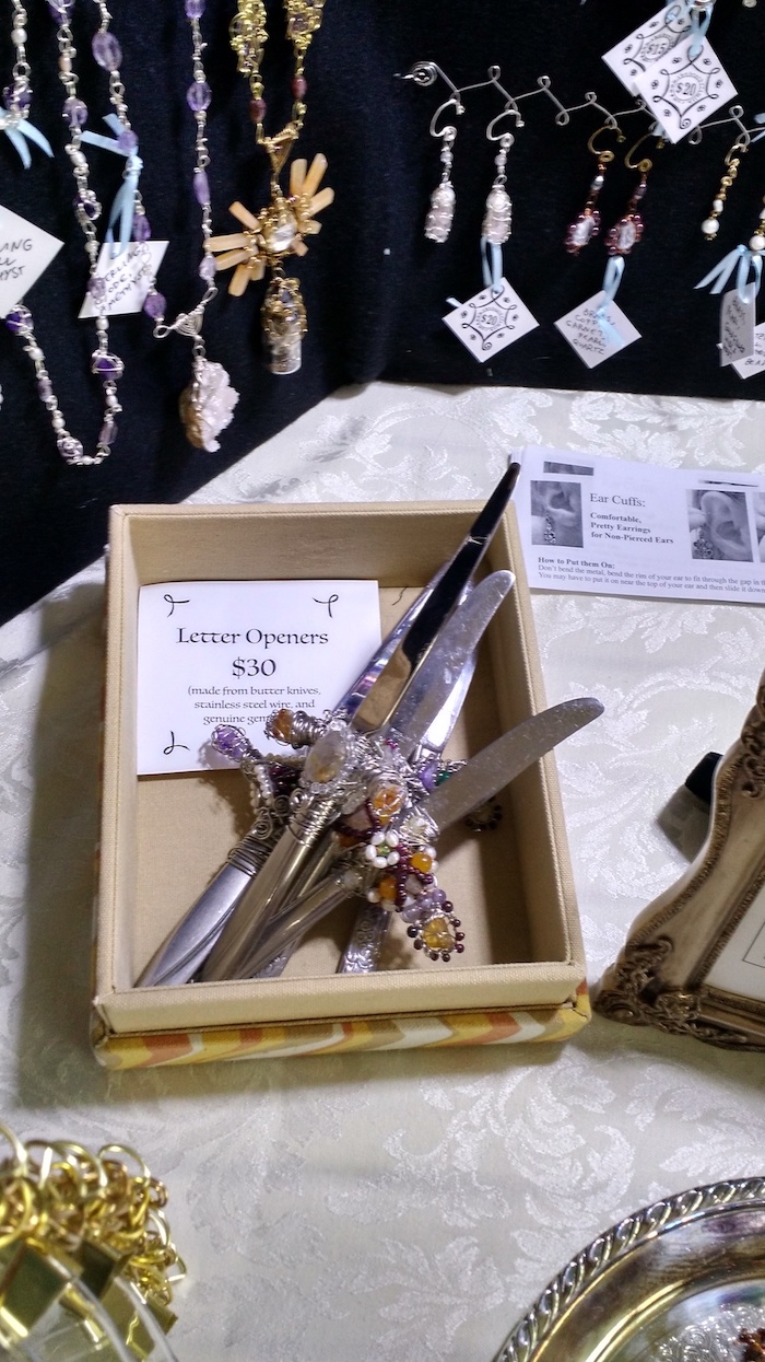 Close-up of a box of jeweled dagger-like letter openers, made from butter knives and steel wire and gemstones.